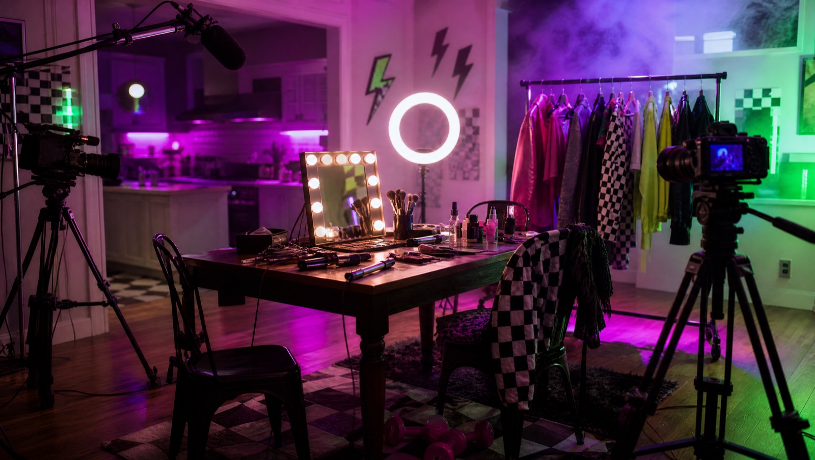 The Mommy Makeovers set: a dining table with makeup, a ring light, a clothing rack and cameras